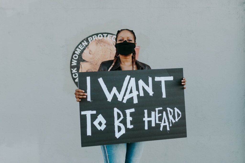 a woman wearing face mask while holding a black placard